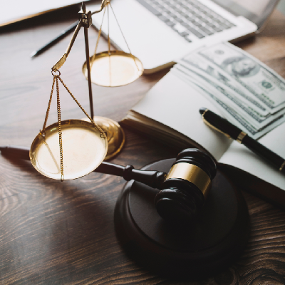 a laptop, money, and a judge scale on a desk